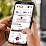 Mano sosteniendo un teléfono en cuya pantalla aparece la app de PlanVital