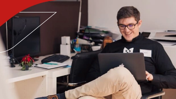 Joven sentado en una oficina frente a un laptop