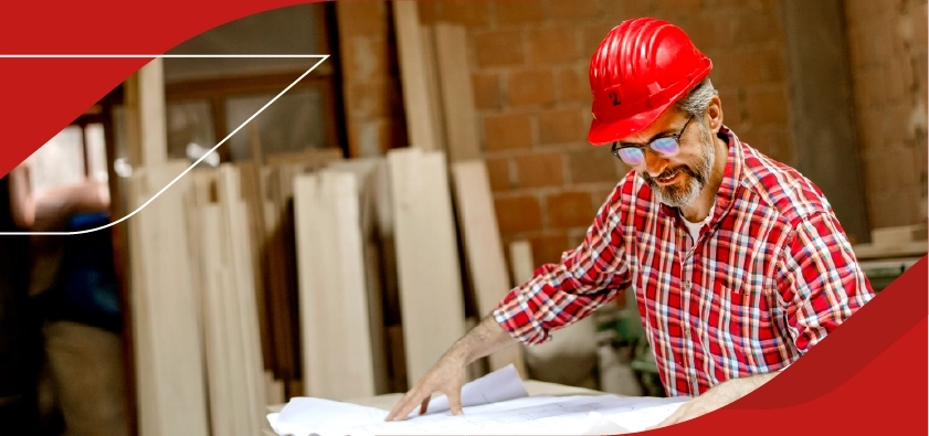 Trabajador con casco de seguridad revisando planos en obra